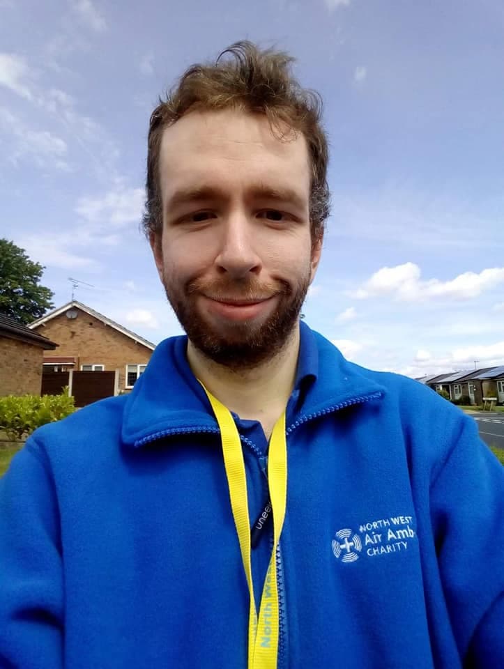 Bearded man wearing a blue North West Air Ambulance Charity fleece and yellow lanyard.