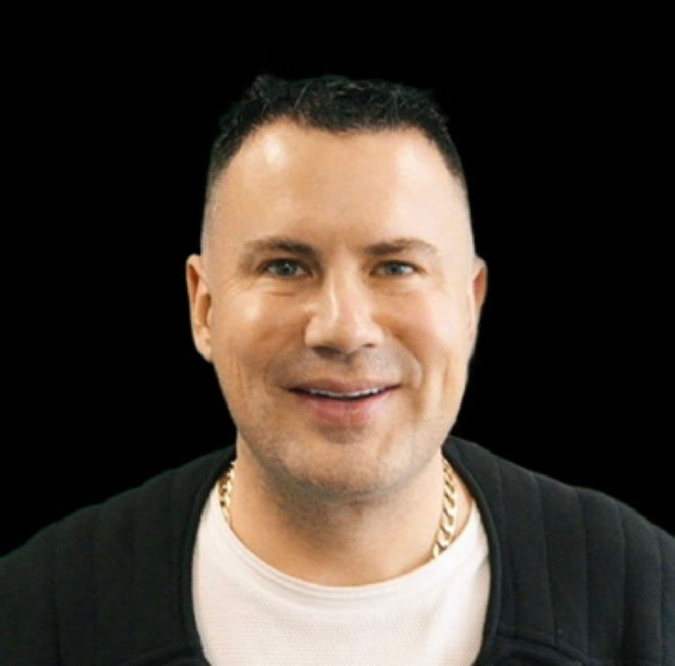 Smiling man with short dark hair and blue eyes wearing a black jacket and chain.